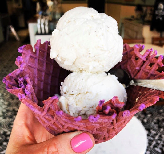 Photograph of person holding ice cream in purple cone bowl